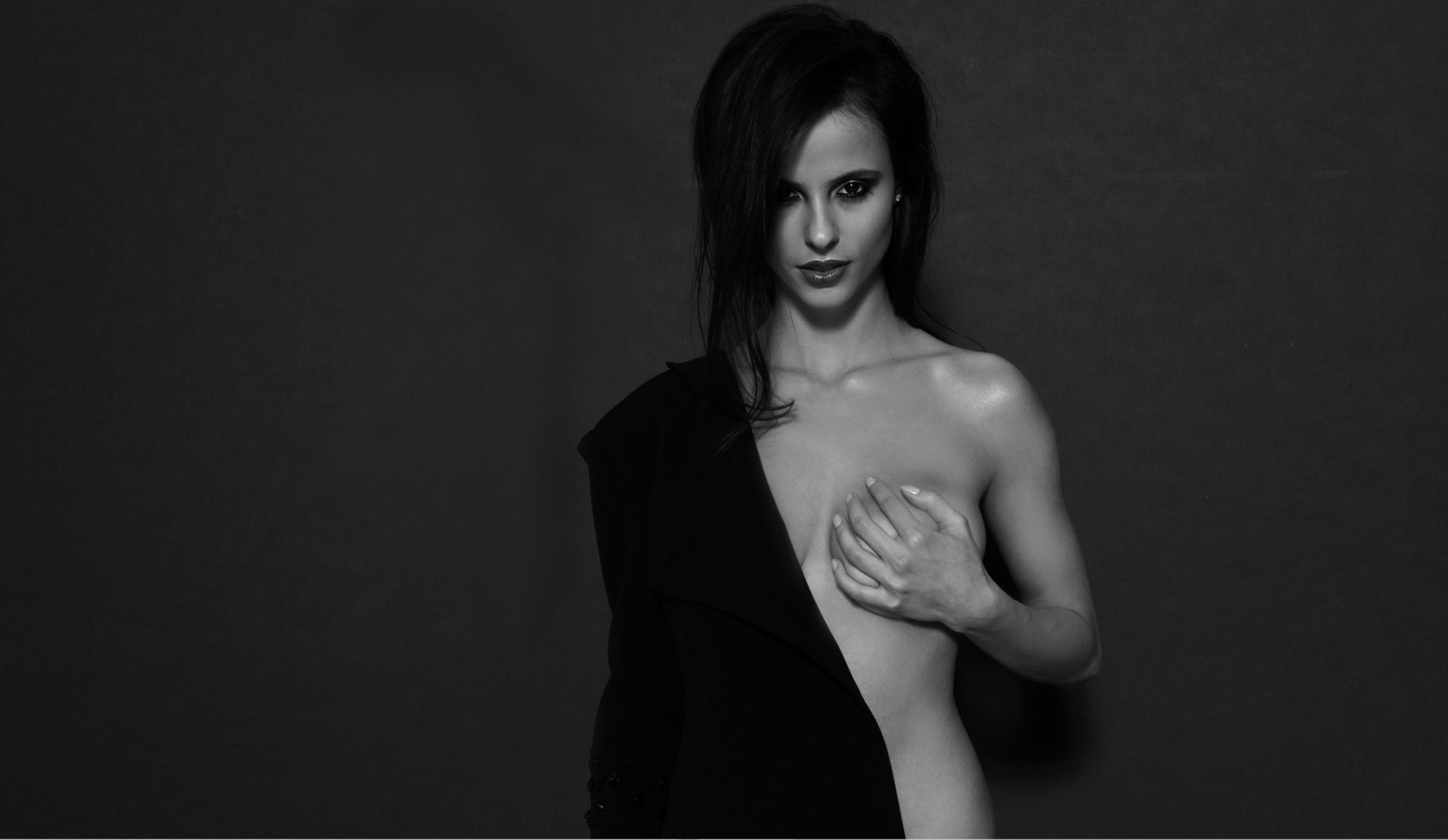 Black-and-white studio portrait of a model in a sculptural black jacket