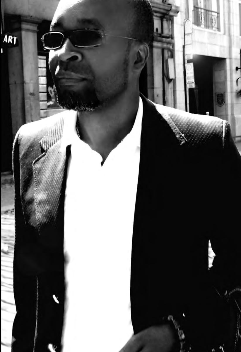 Linton Allwood in a black-and-white street portrait, wearing sunglasses and a dark jacket.