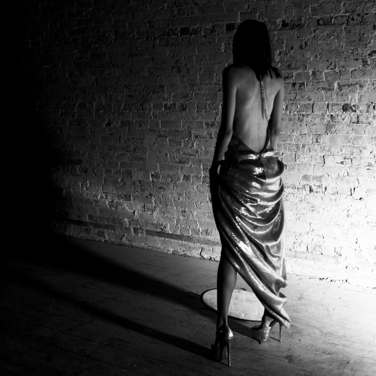 A draped figure, brick wall and long shadows — SHADOW LIGHT 01